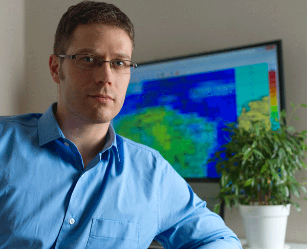 Meteorologist in front of a weather chart and plant